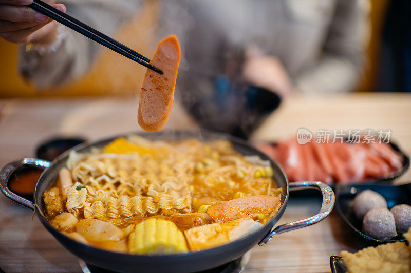 年轻的亚洲妇女吃韩国菜，军队炖(Budae Jjigae)在餐厅